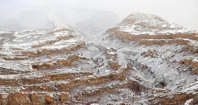 Ash-covered slopes inside the Ijen crater, streaked white and orange